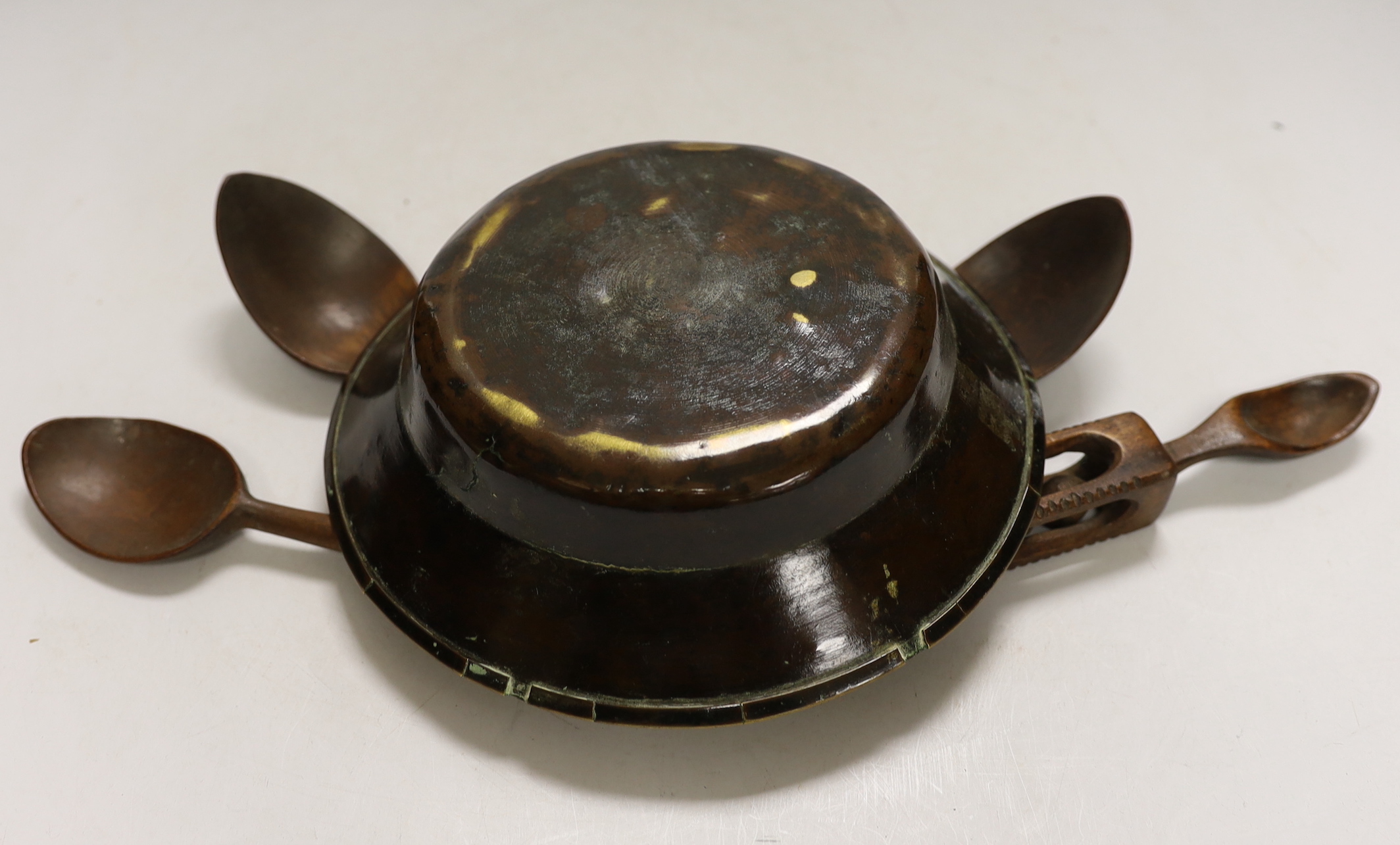 A small early brass bowl, together with a selection of four various treen spoons, bowl 20cm